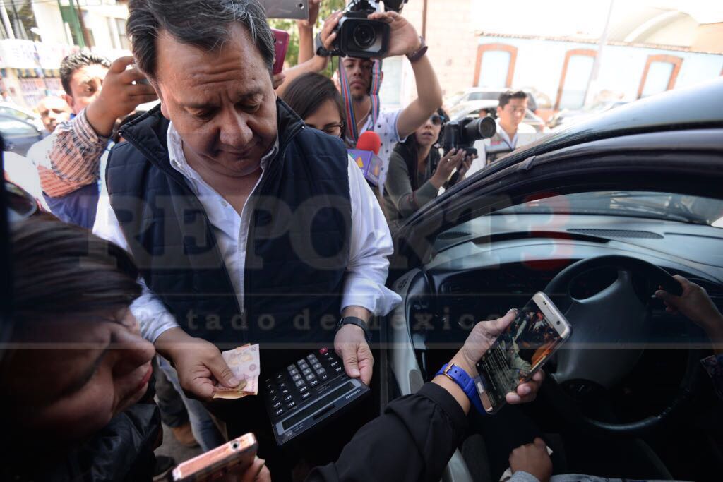 El candidato del PT Oscar González entrega dinero en efectivo a ciudadanos.